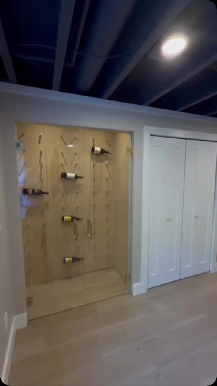 Finished basement with painted walls, white doors and a dark painted ceiling