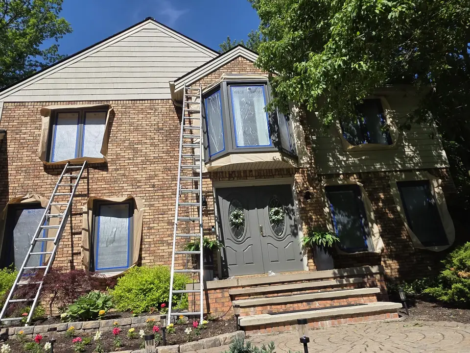 Crist Painting ladders on a brick colonial during an exterior repaint
