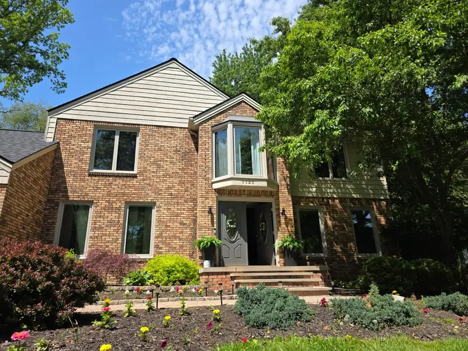 Brick colonial home with freshly painted trim, shutters and front door