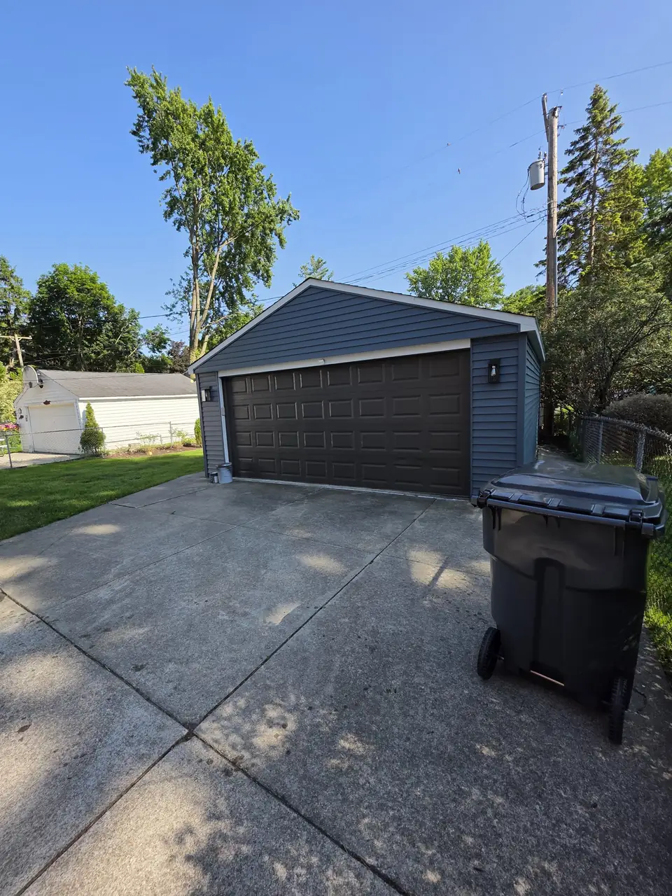 Detached garage painted navy blue with a dark garage door
