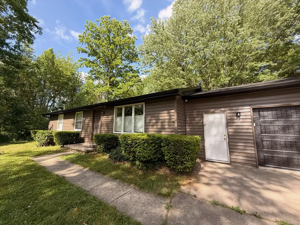 Ranch home with brown siding and a white side door
