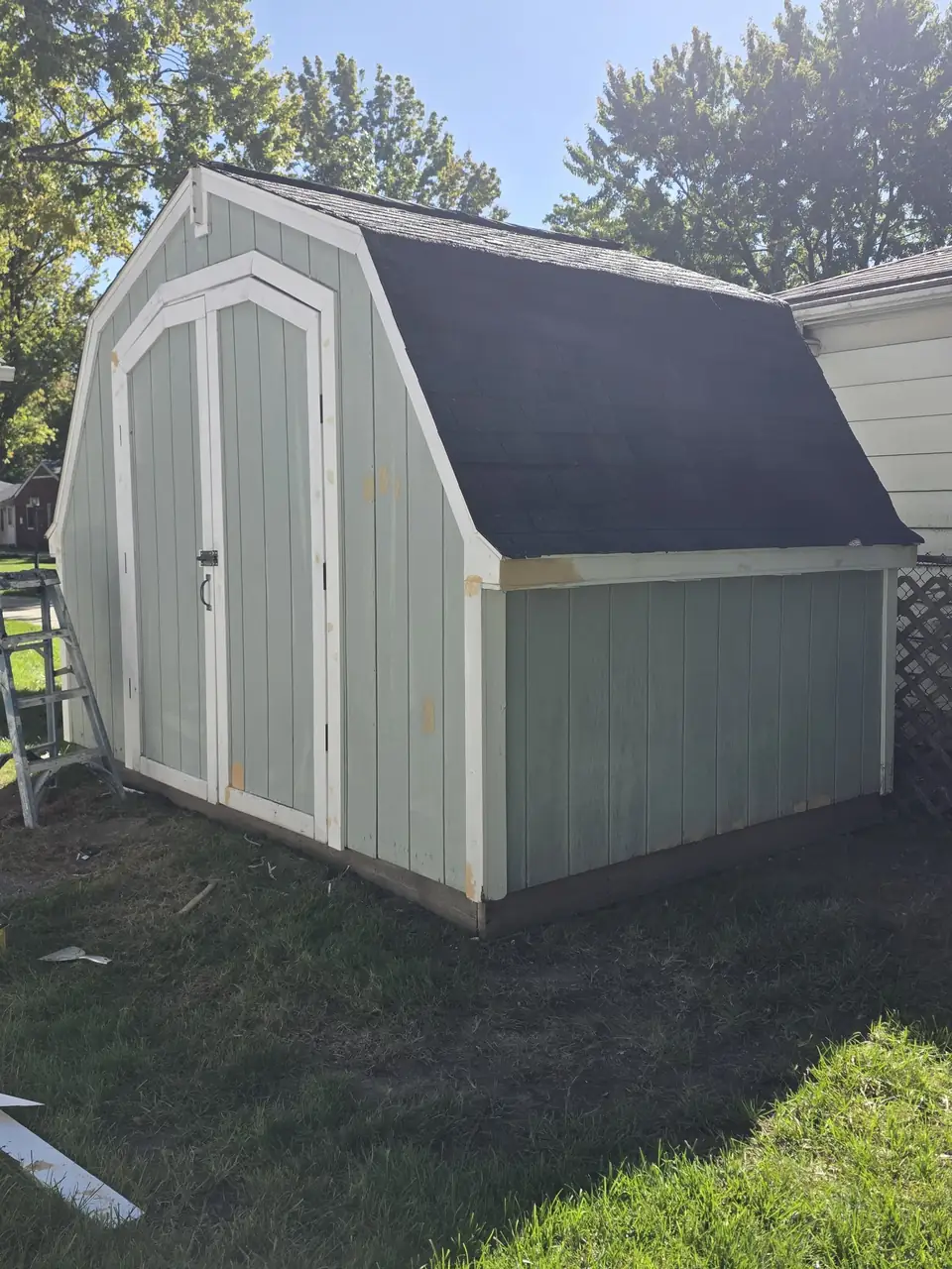 Gambrel shed with sage green siding and white trim