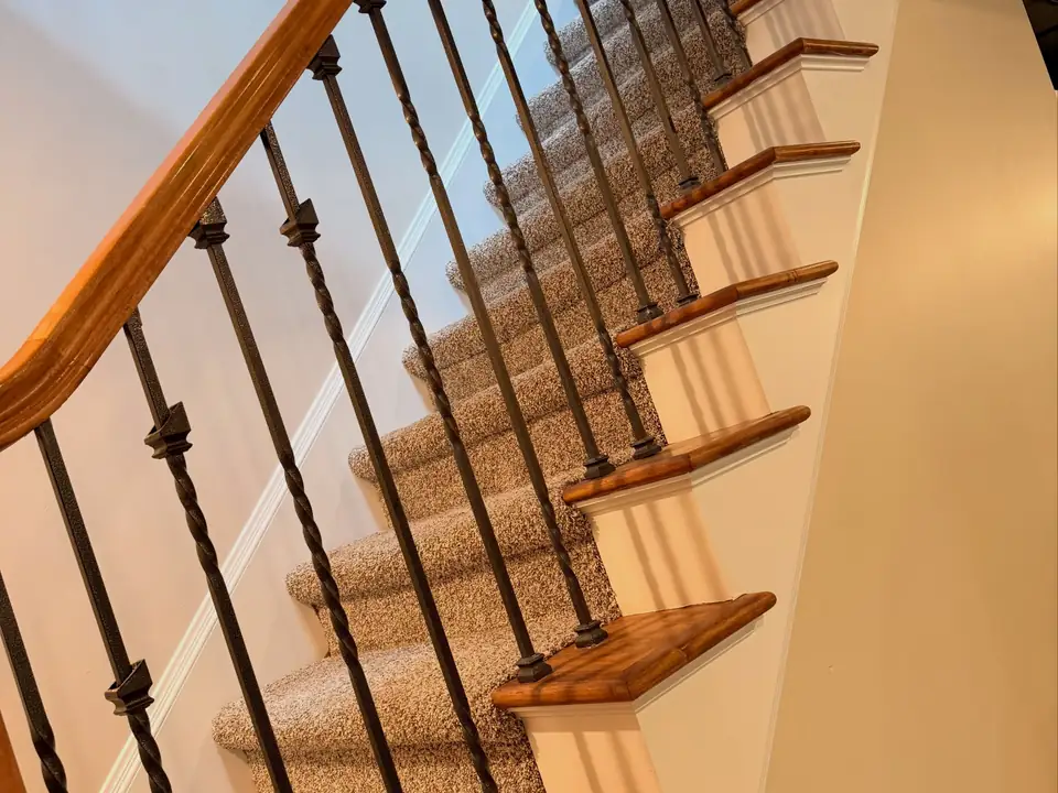 Close-up of freshly painted white stair risers beside a wood handrail