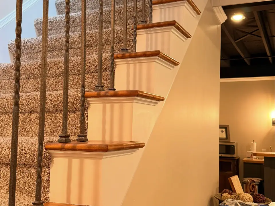 Staircase with crisp white risers, stained treads and iron balusters